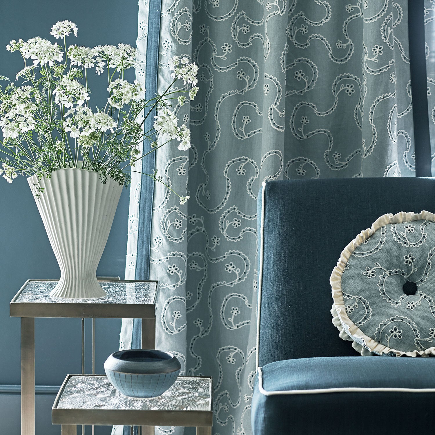 Living room with dark blue sofa, decorative pillows, and embroidered curtains in blue.