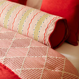 Close-up of a quilt with geometric pattern on a bed.