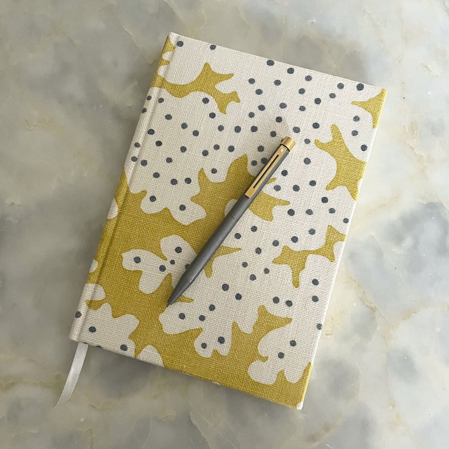 A yellow and cream linen notebook with a stylized coral pattern.