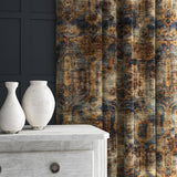 A curtain made from a printed velvet fabric in blue, brown and black featuring an opulent pattern.