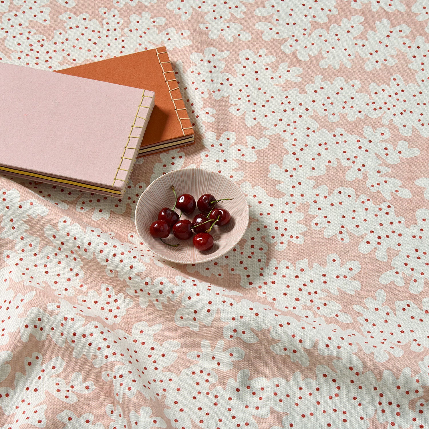 A printed linen fabric sample in pink, red and off white featuring a stylized coral pattern.