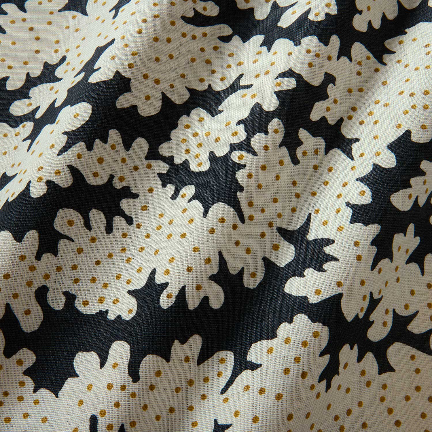 A printed linen fabric sample in black, brown and off white featuring a stylized coral pattern.