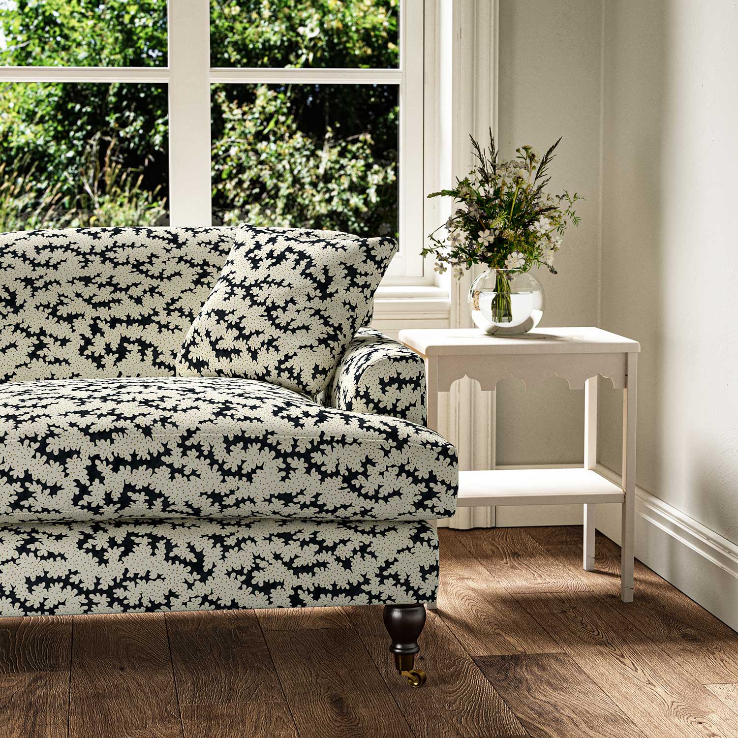 Sofa upholstered in a printed linen fabric sample in black, brown and off white featuring a stylized coral pattern.