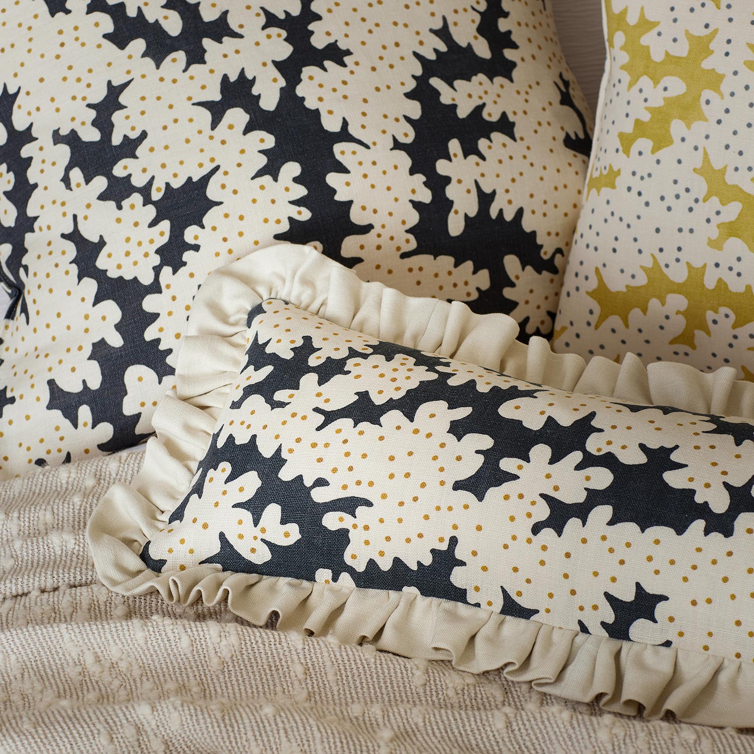 Cushions made from a printed linen fabric sample in black, brown and off white featuring a stylized coral pattern.