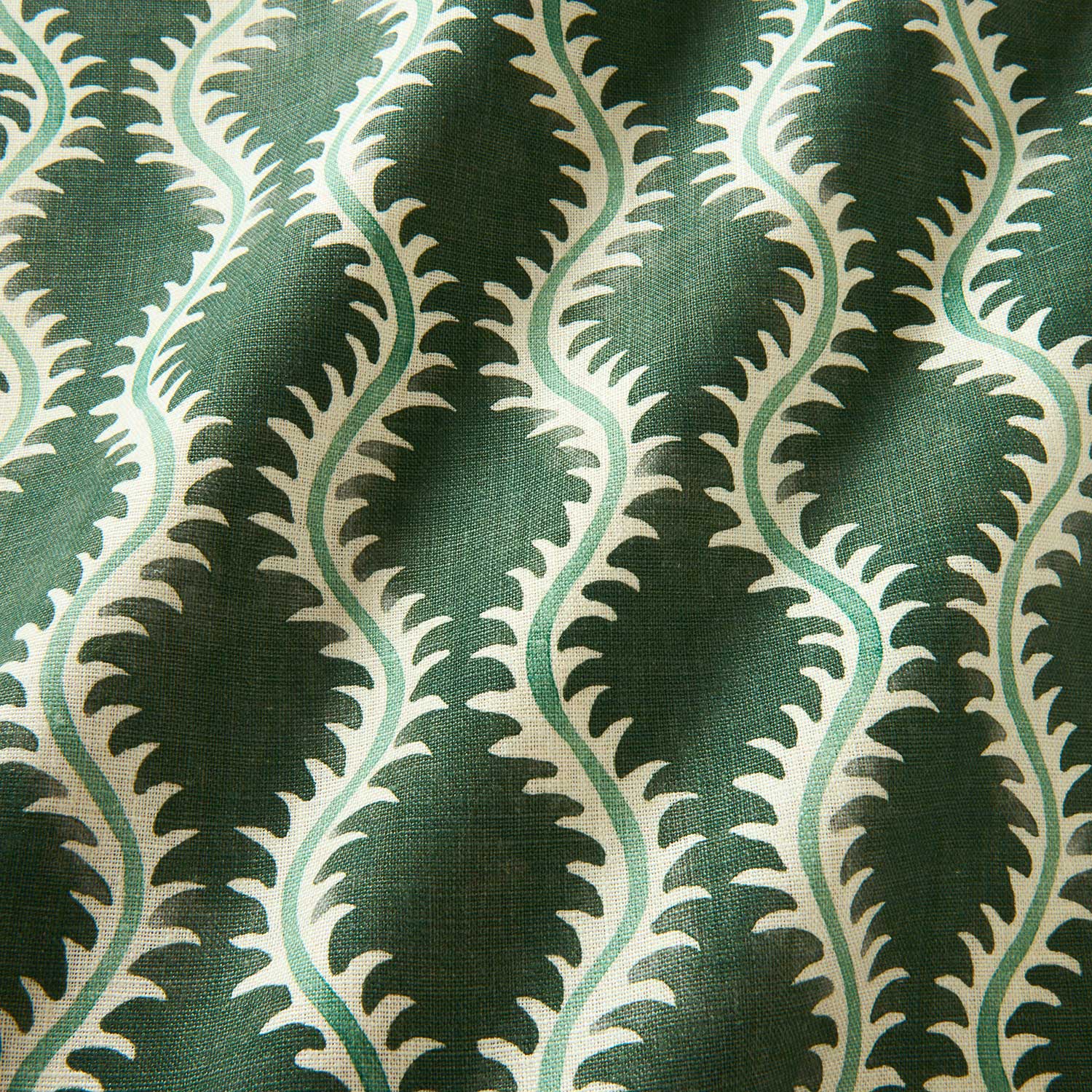 A printed linen fabric sample in green and off white featuring a stylized fern pattern.