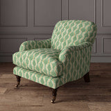 Chair upholstered in a printed linen fabric sample in green, brown and off white featuring a stylized fern pattern.