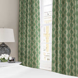 Curtains made from a printed linen fabric sample in green, brown and off white featuring a stylized fern pattern.