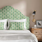 Headboard upholstered in a printed linen fabric sample in green, brown and off white featuring a stylized fern pattern.
