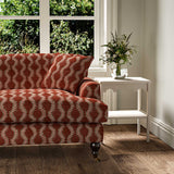 Sofa upholstered in a printed linen red and pink featuring a stylized fern pattern.