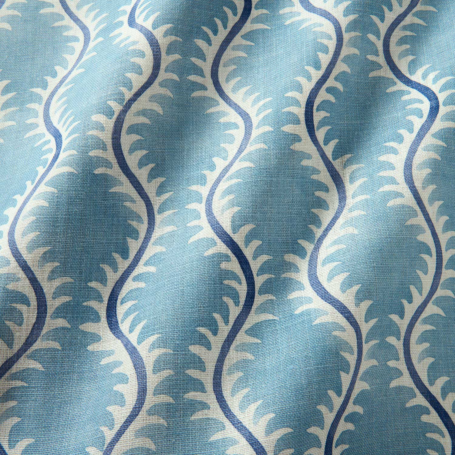 A printed linen fabric sample in blue and off white featuring a stylized fern pattern.