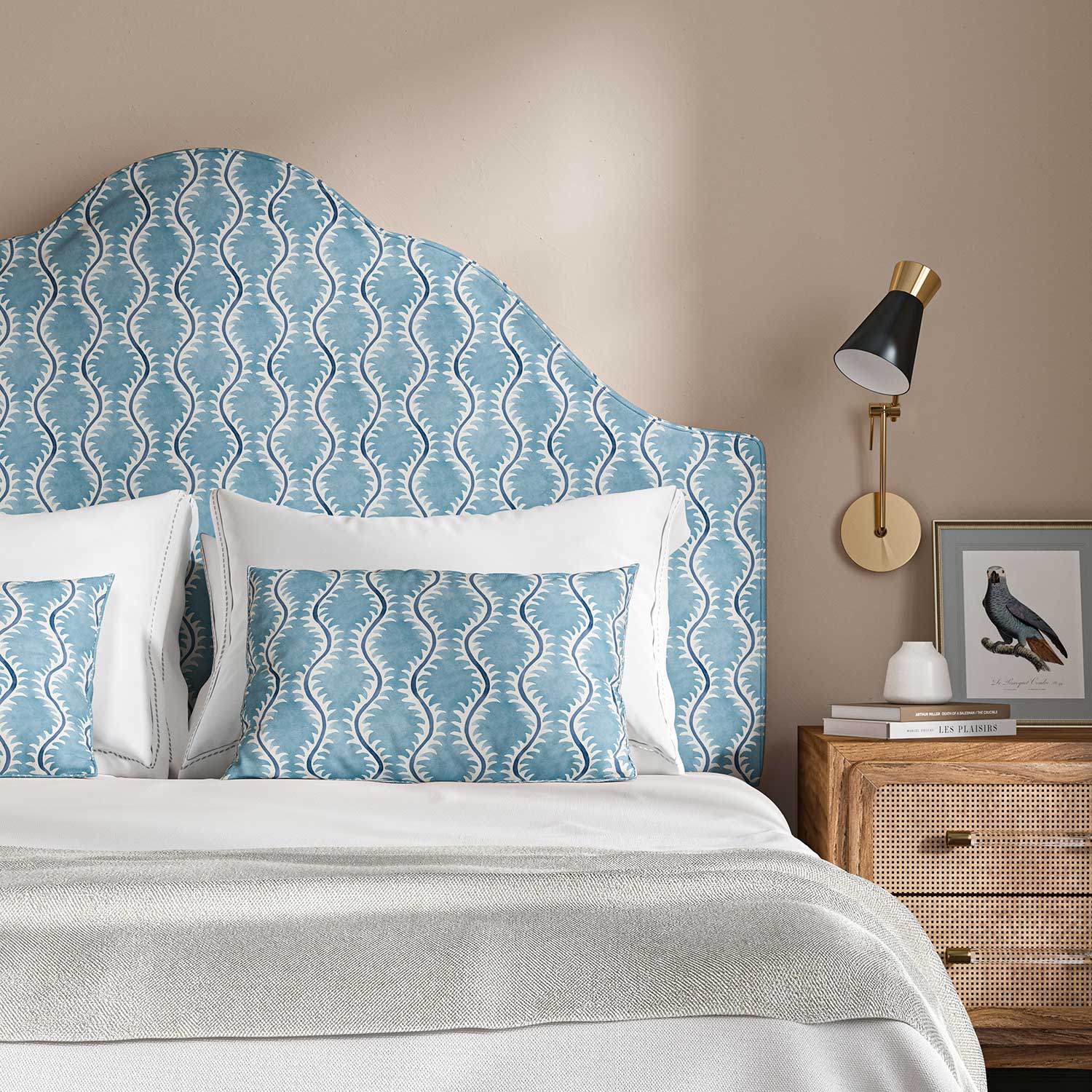 Headboard upholstered in a printed linen fabric sample in blue and off white featuring a stylized fern pattern.