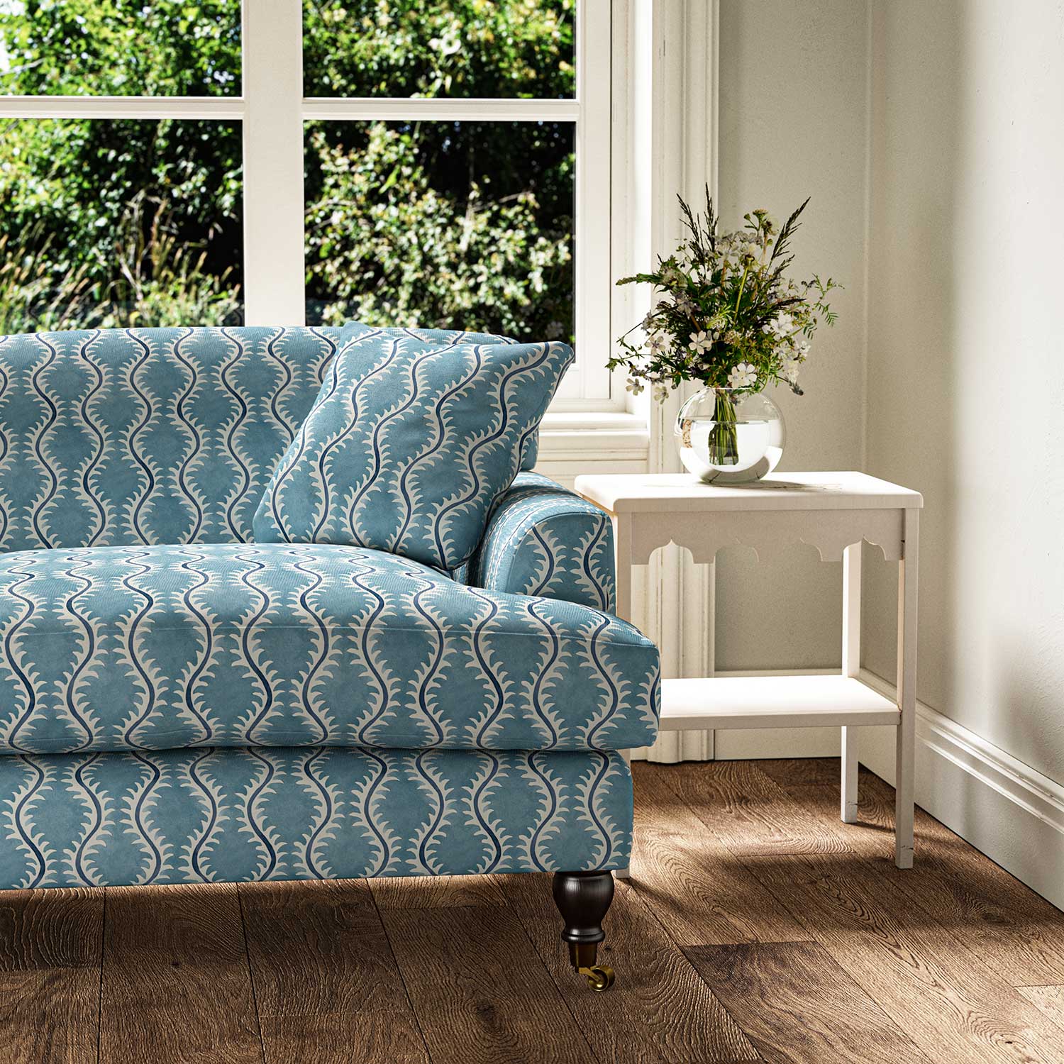 Sofa upholstered in a printed linen fabric sample in blue and off white featuring a stylized fern pattern.
