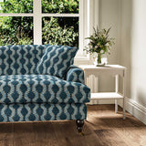Sofa upholstered in a printed linen fabric in blue and off white featuring a stylized fern pattern.