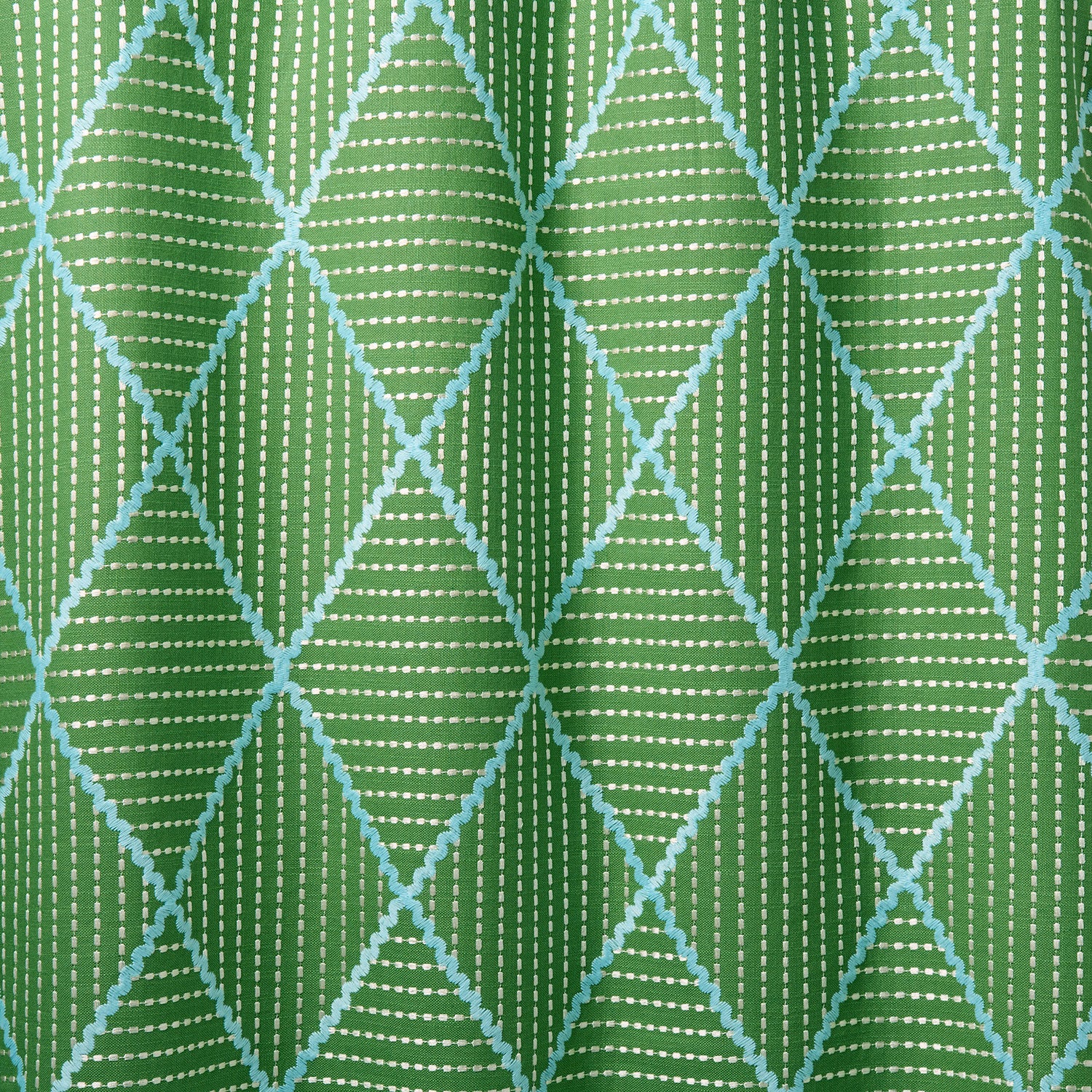 Geometric embroidery pattern with green and blue lines on a green background.