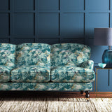 Sofa covered in a printed velvet fabric featuring a classic oak leaf design in teal.
