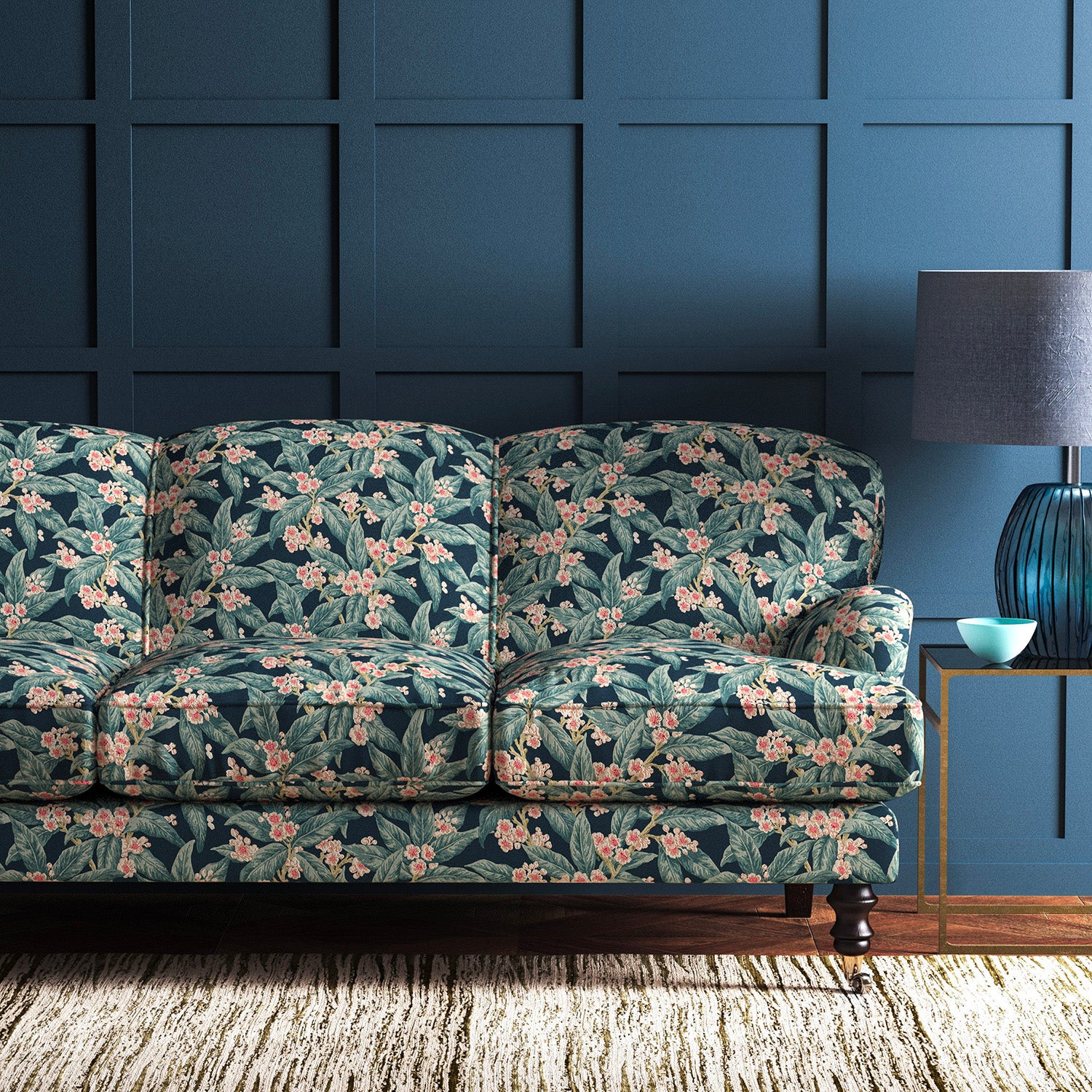 Sofa covered in a velvet upholstery fabric with a blue leaf and blossom design.
