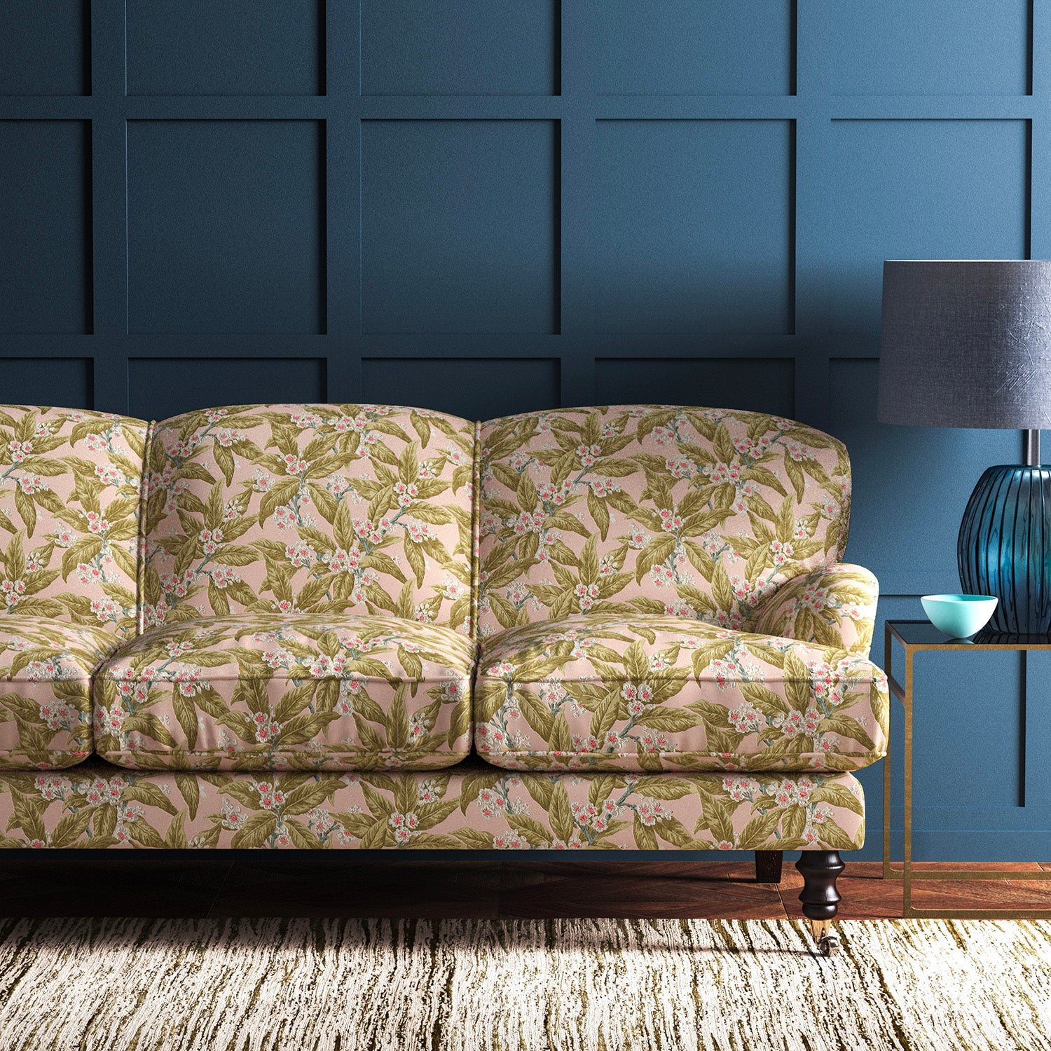Sofa covered in a velvet upholstery fabric in a peach and ochre leaf and blossom design.
