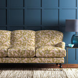 Sofa covered in a velvet upholstery fabric in a peach and ochre leaf and blossom design.