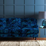 Sofa upholstered in an electric blue printed velvet upholstery fabric with palm leaf design.