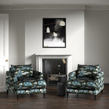 Velvet armchairs upholstered in a printed velvet fabric with a scenic landscape design in blue colours.