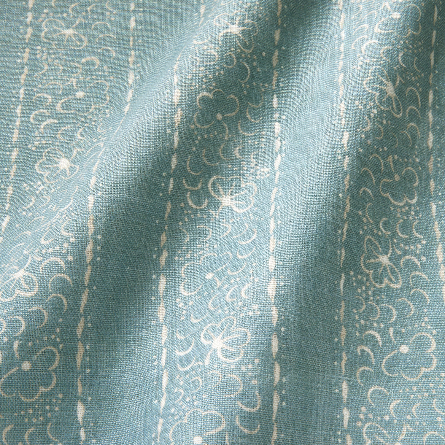 Printed linen fabric sample – a delicate pattern of moons and star-like dots in blue and cream