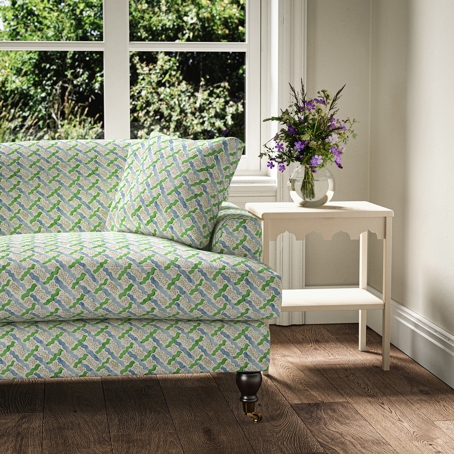 Printed linen fabric - a contemporary lattice design in green, blue, cream and white – on a sofa