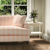 Printed linen fabric – a bold blocks of colour in this inviting stripe are softened with a painterly finish in pink, yellow and white – on a sofa