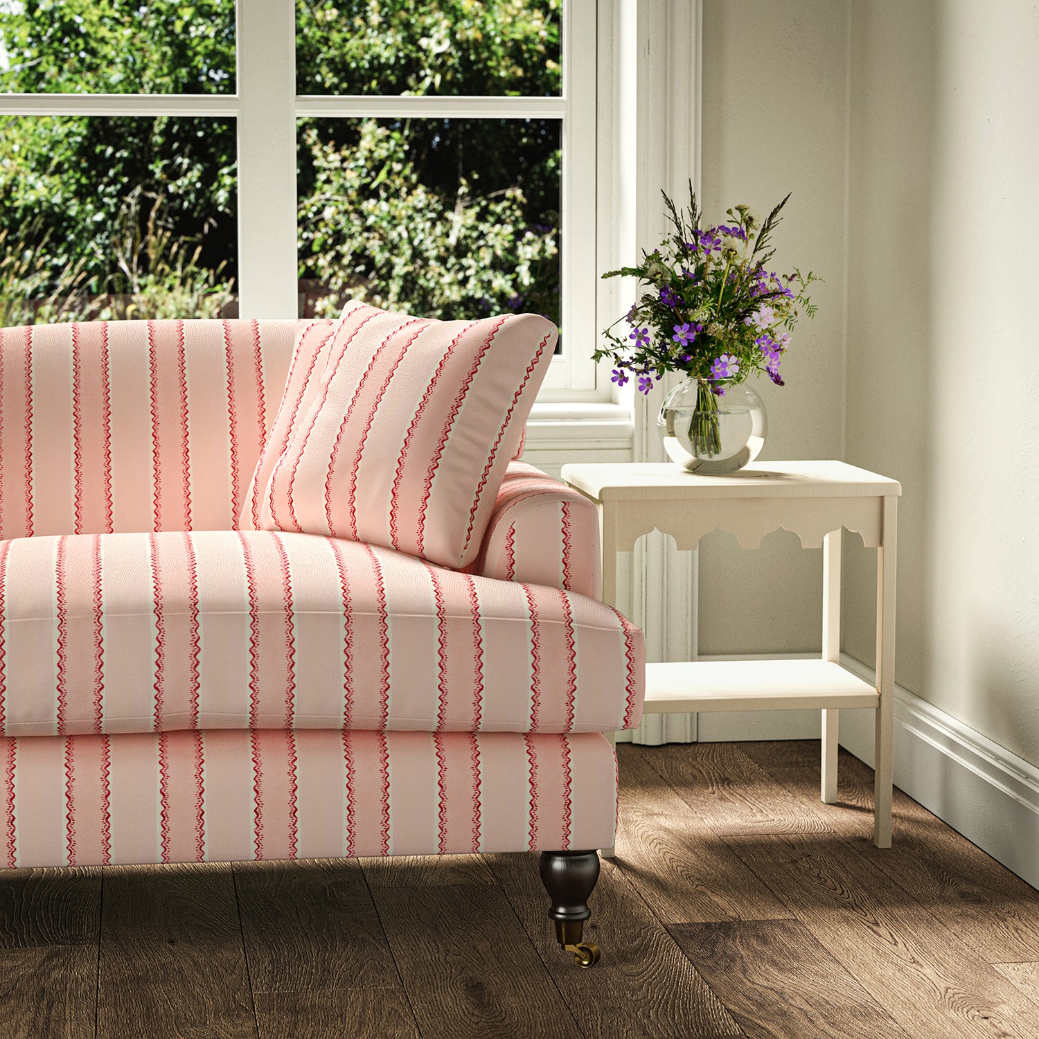 Printed linen fabric – a bold blocks of colour in this inviting stripe are softened with a painterly finish in pink, red and white – on a sofa