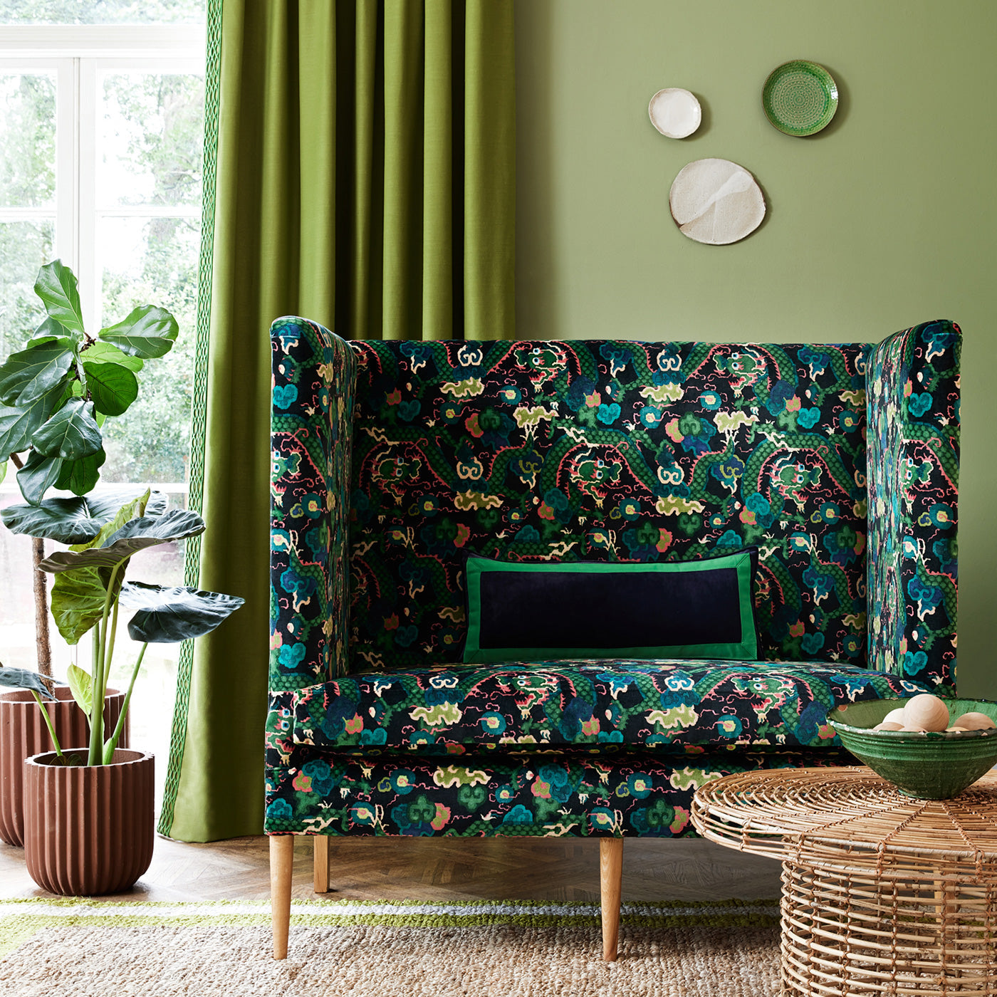 Velvet sofa upholstered in a printed velvet fabric with a intricate mirror dragon design in green colours.