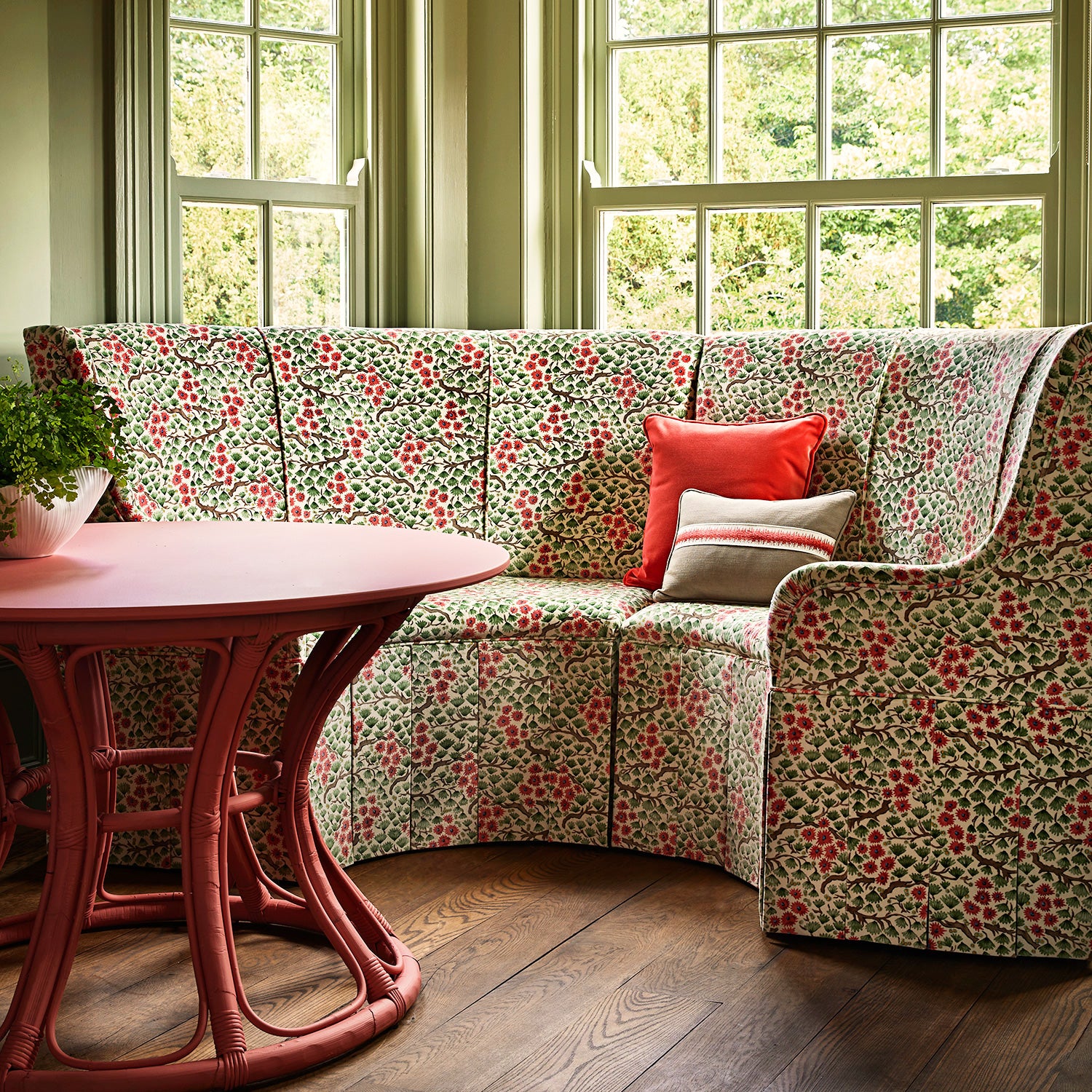 A printed velvet fabric which captures the beauty of the forest floor: leaves, brand and flowers abound in pink, green and brown on a sofa