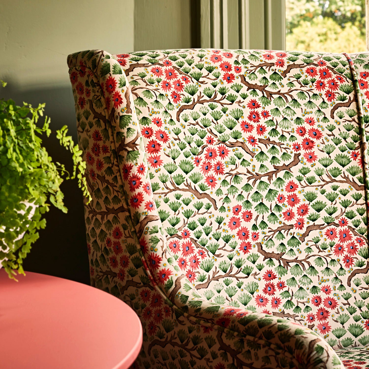 A printed velvet fabric which captures the beauty of the forest floor: leaves, brand and flowers abound in pink, green and brown on a sofa