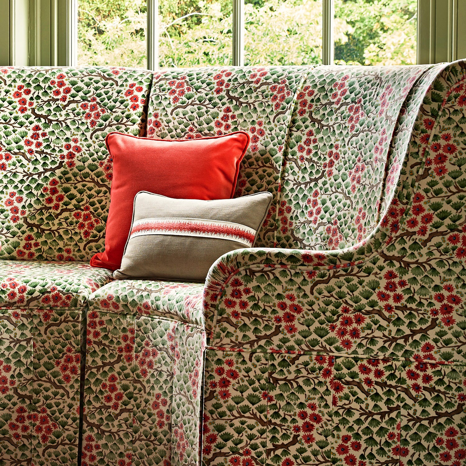 A printed velvet fabric which captures the beauty of the forest floor: leaves, brand and flowers abound in pink, green and brown on a sofa