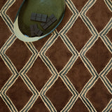 Brown and blue irregular diamond motif printed velvet fabric styled with a ceramic bowl.