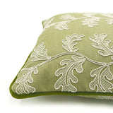 Green embroidered cushion with white leaf pattern.