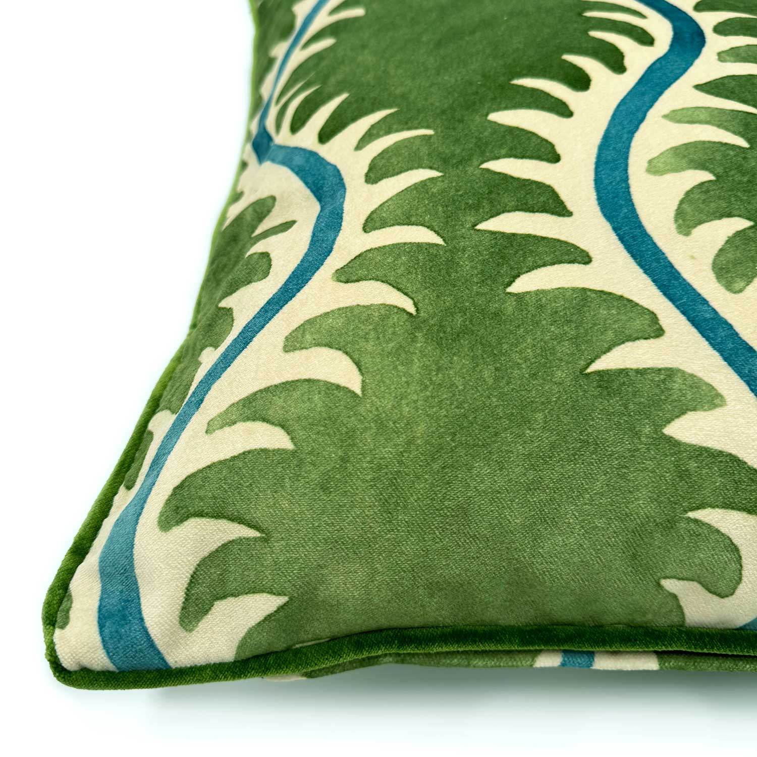 A green, blue and off white velvet cushion with a all-over repeat pattern and velvet piping.