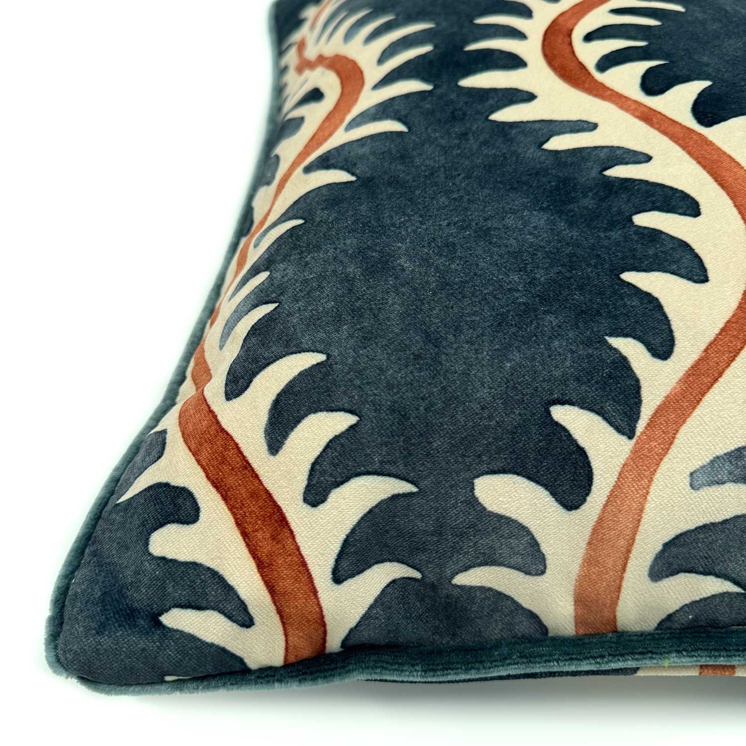 A orange, blue and off white velvet cushion with a all-over repeat pattern and velvet piping.