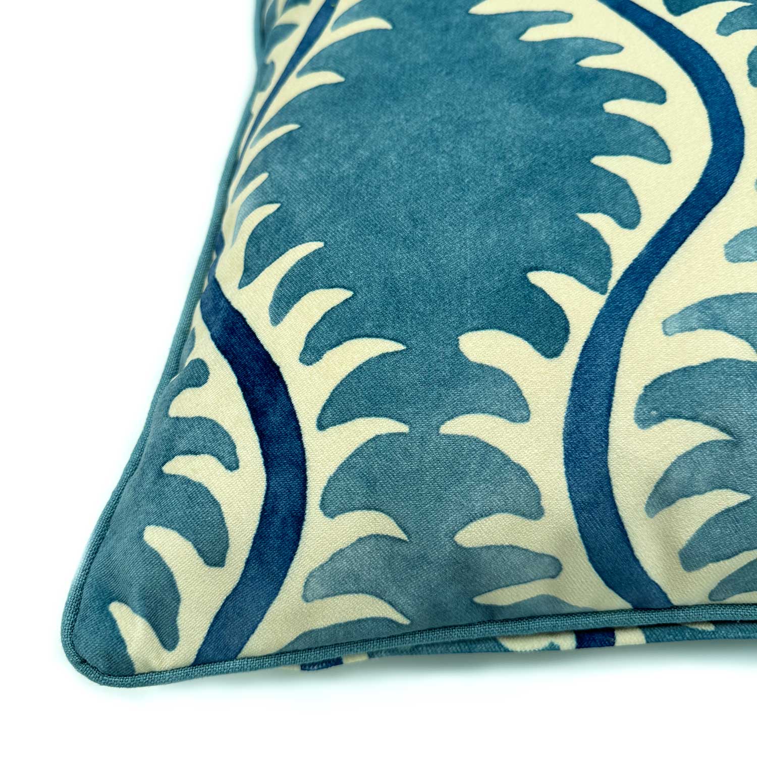 A blue and off white velvet cushion with a all-over repeat pattern and velvet piping.