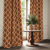 Ginger/brown printed velvet curtains with an irregular diamond pattern framing a tall window.