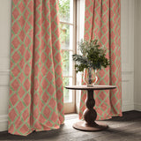 Orange and green printed velvet curtains with an irregular diamond pattern framing a tall window.