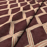 Close-up of maroon and pink printed velvet fabric featuring an irregular diamond motif with a soft, luxurious pile. 