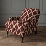 Accent chair upholstered in maroon and pink printed velvet with an irregular diamond pattern, showcasing the fabric’s rich texture. 