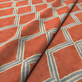 Close-up of orange and blue printed velvet fabric featuring an irregular diamond motif with a soft, luxurious pile. 