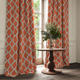 Orange and blue printed velvet curtains with an irregular diamond pattern framing a tall window.