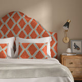 Bedroom with a curved upholstered headboard covered in orange and blue printed velvet featuring an irregular diamond motif.