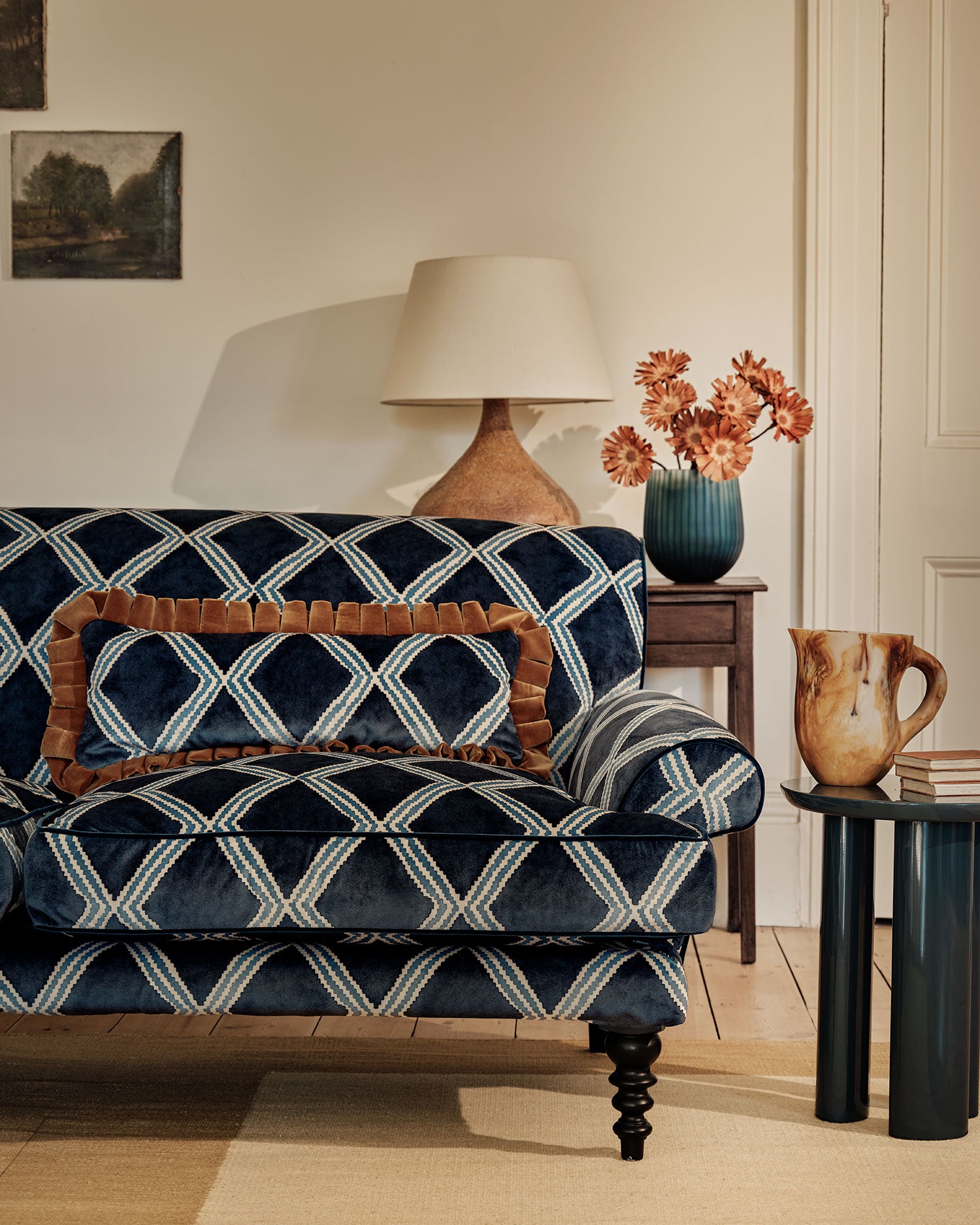 Sofa upholstered in blue printed velvet featuring an irregular diamond motif, styled in a timeless living room.