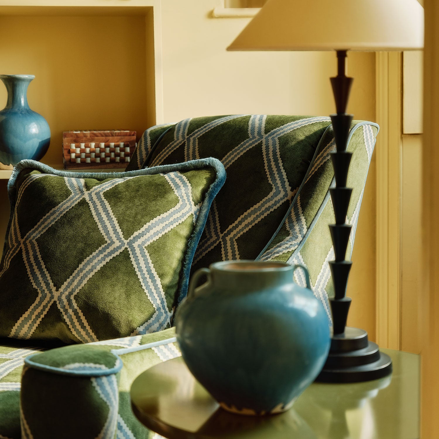 Detail of accent chair upholstered in green and blue printed velvet with an irregular diamond pattern, showcasing the fabric’s rich texture. 