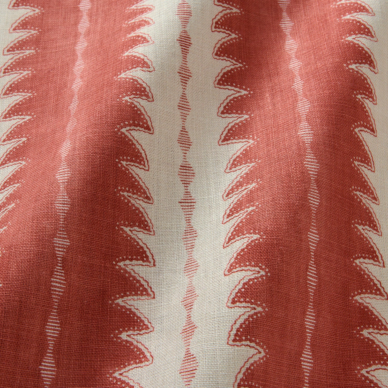 A printed linen fabric sample in red and off white featuring a striped fern design.