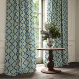 Curtains made from a printed linen fabric in blue and off white featuring a mirrored ribbon pattern.
