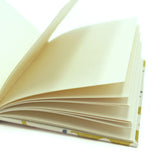 A yellow and cream linen notebook with a stylized coral pattern.