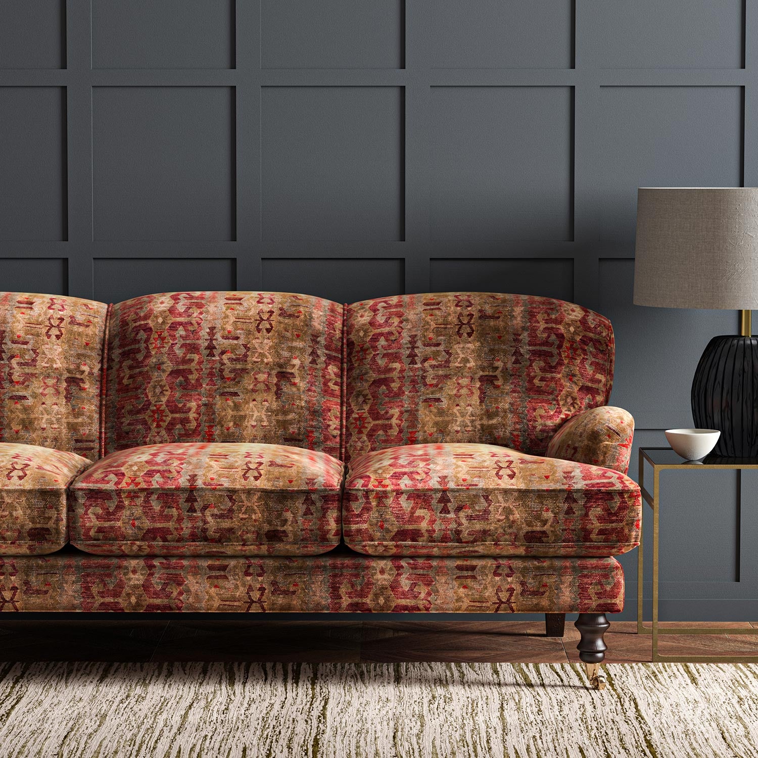 Sofa upholstered in a printed velvet fabric in red and brown featuring a stripe kilim pattern.